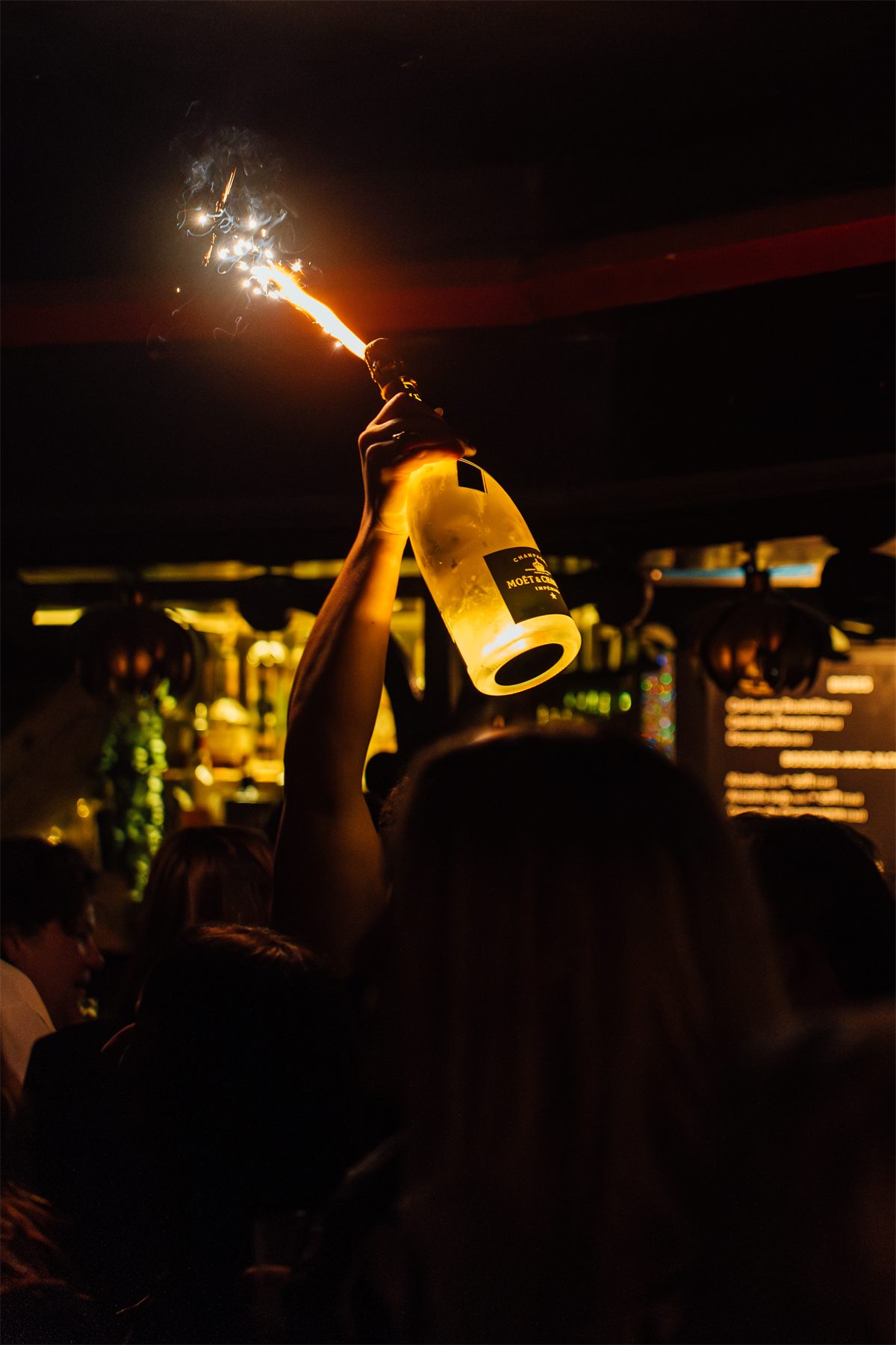 Bouteille de champagne brandie avec un cierge magique lors d'une soirée